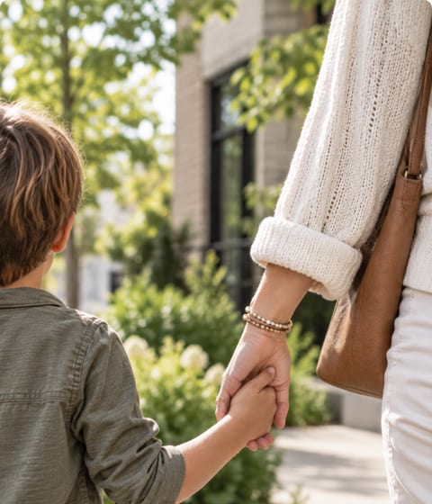 A parent and child walking hand in hand along a garden path.